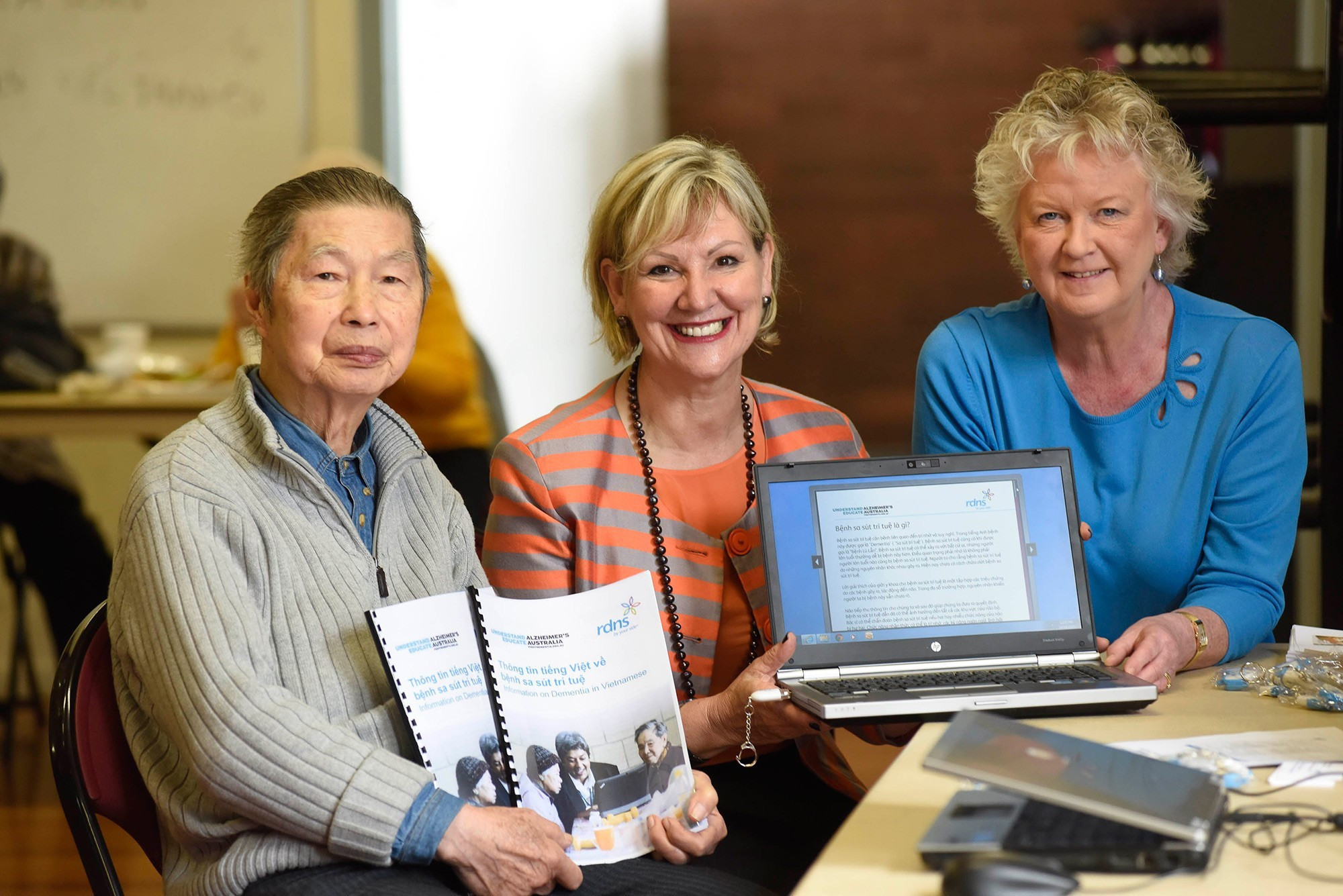 <p>Dr Susan Koch (right) and Alzheimer’s Australia Victoria CEO Maree McCabe (centre) show off the new RDNS Talking Book with a member of the Vietnamese community group.</p>
