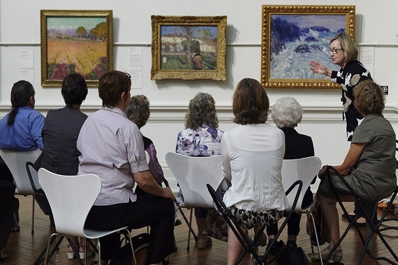 <p>A guide talks to gallery visitors as part of the Art and Dementia program.</p>
