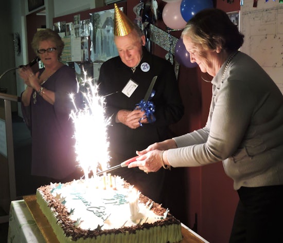<p>Original resident Sid Fleming and Marlene Bentley help to cut the cake as Village Manager Debbie Dean looks on.</p>
