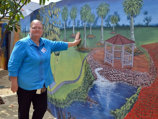 <p>Ms Stevenson with a mural she organised at the hostel</p>
