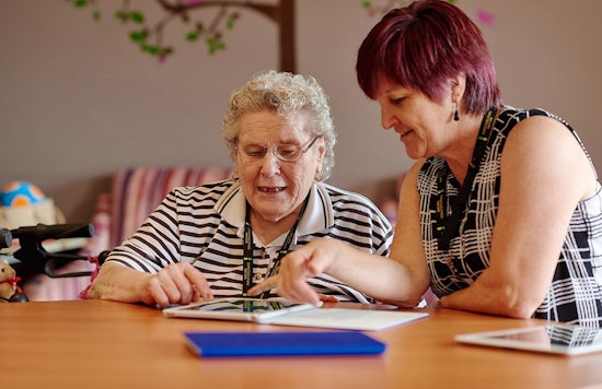 <p>Angela Shelton heklps residents at Ridgeview in Albion Park use iPads.</p>

