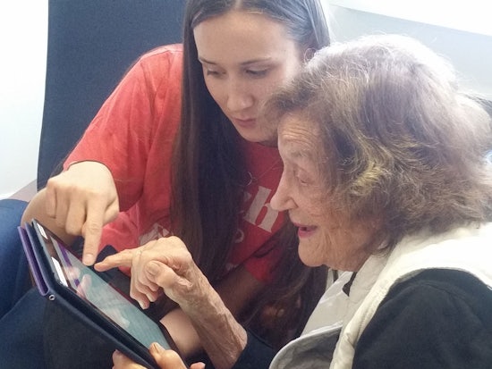 <p>Riley Gentle (22) shows 89-year-old Jane Lotheringer how to use an iPad</p>
