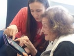 Riley Gentle (22) shows 89-year-old Jane Lotheringer how to use an iPad