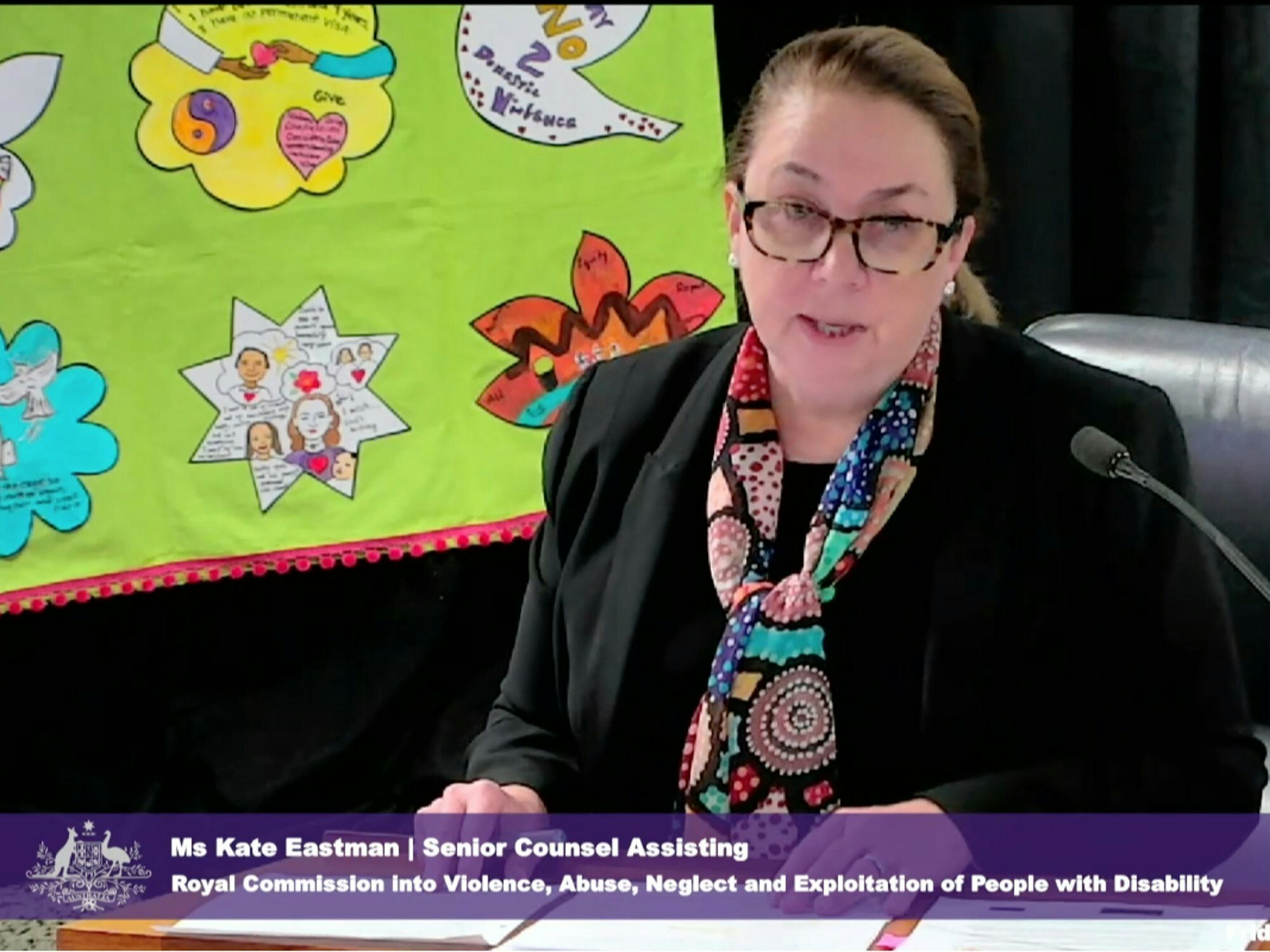 <p>Senior Counsel Assisting, Kate Eastman, appeared for Public Hearing 17 in front of artwork submitted by women with disability who experienced domestic violence. [Source: Disability Royal Commission]</p>
