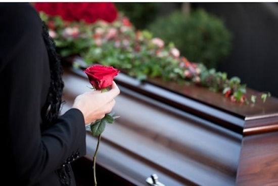 <p>Mourning woman holds rose at funeral</p>
