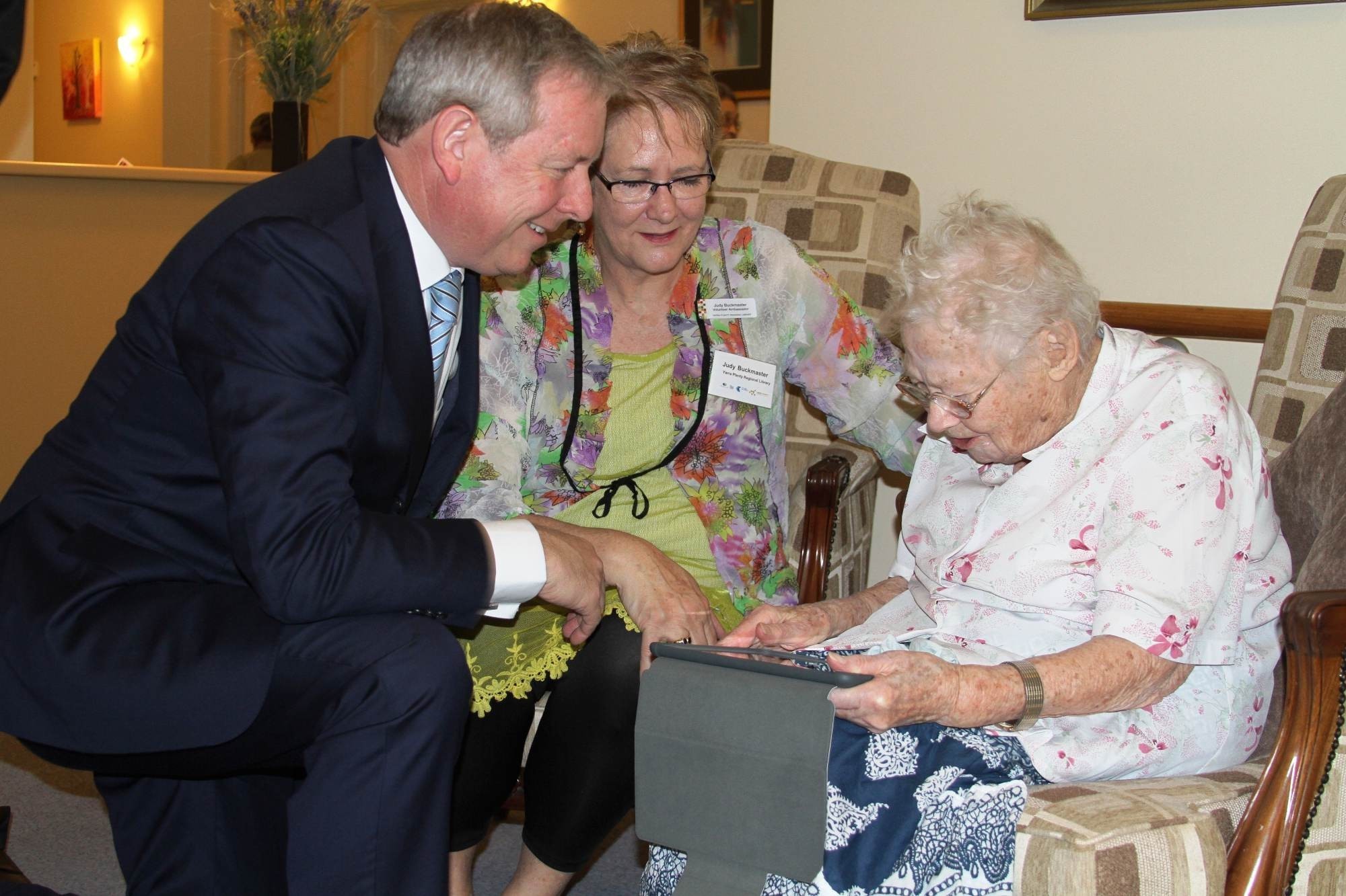 <p>Victorian Minister for Ageing, David Davis, together with Yarra Plenty Regional Library’s, Judy Buckmaster, assist in showing Wattle Glen aged care resident, Trixie King, an iPad.</p>
