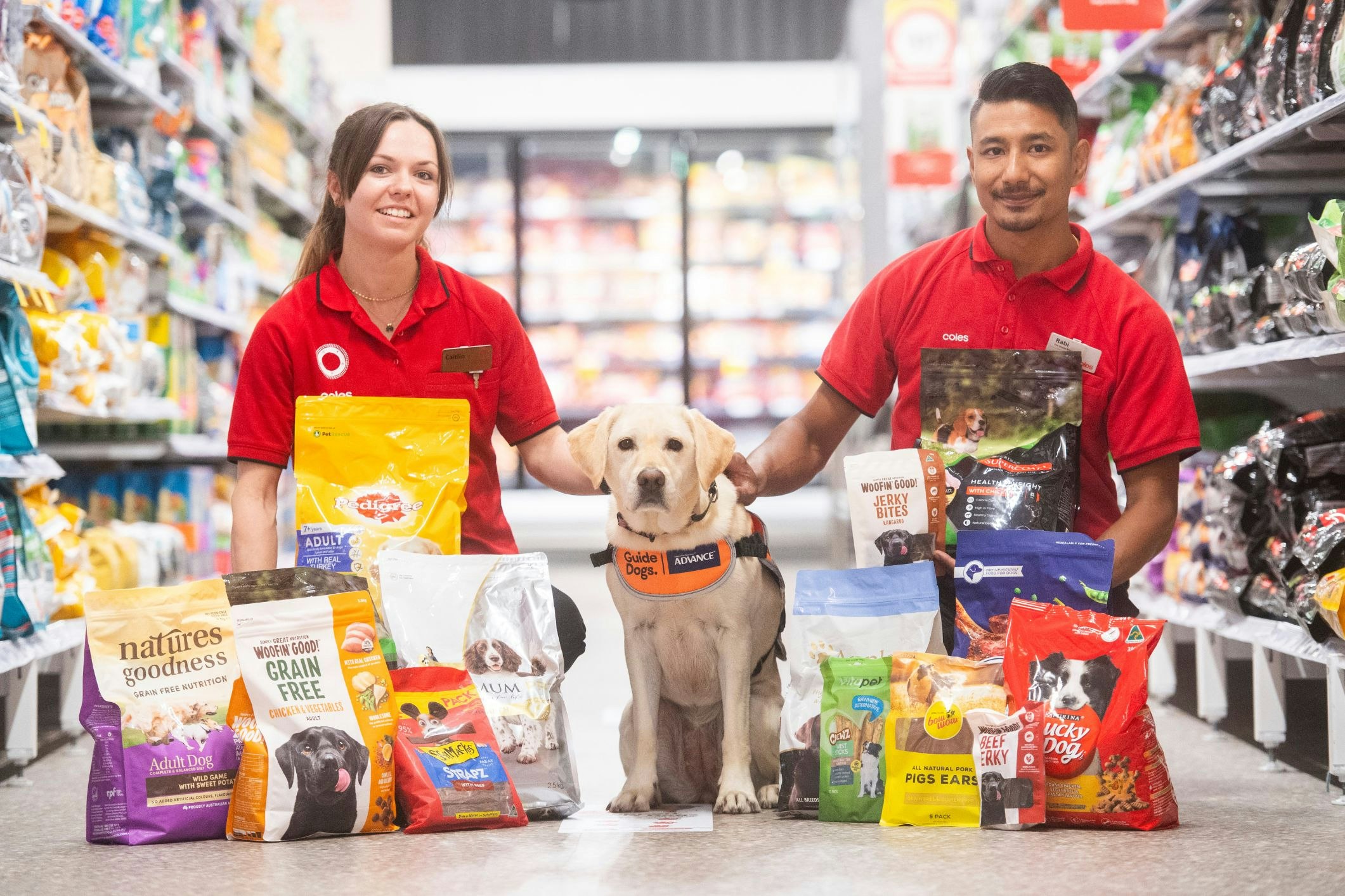 <p>Coles team members Caitlin and Rabi with puppy-in-training Orion. [Source: Coles Group]</p>
