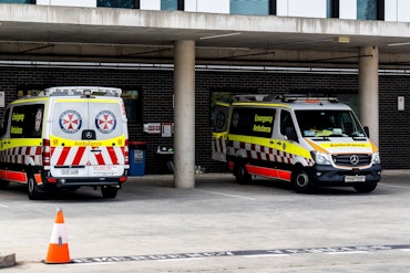 Two ambulances parked under cover at a hospital.