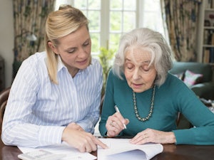Woman helping older woman with her documents.
