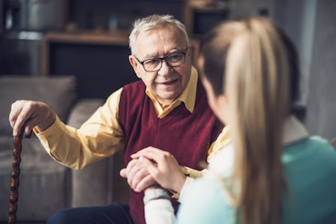 An older man speaks to a younger woman with her back to the camera