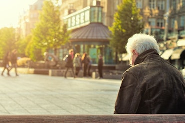 An older man looks on from afar at a crowd.