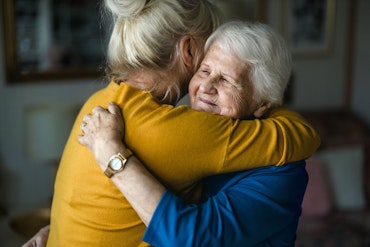 An older woman hugs her daughter.