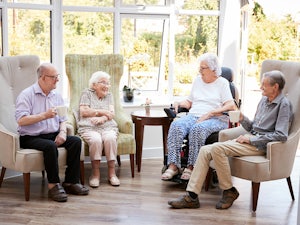 Group of aged care residents sitting together smiling and talking (Source: Shutterstock)