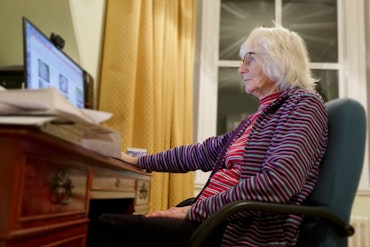 An older woman sits in front of a laptop.