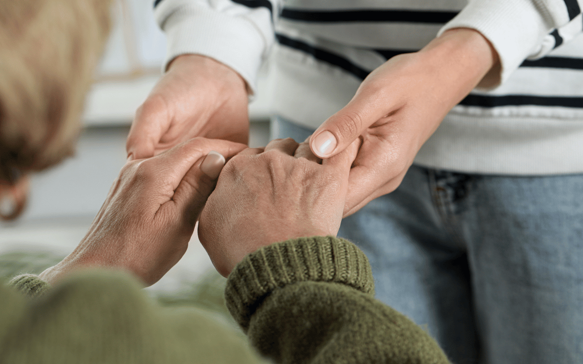 A person holding an older person's hands