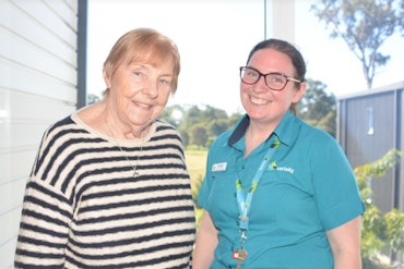 An aged care worker stands next to an older person