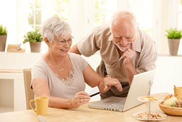Two older people look at a computer screen