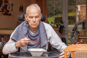 Older man with dementia eats at home
