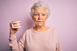A woman holds up a pair of dentures