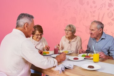 A group of older people eat around a table