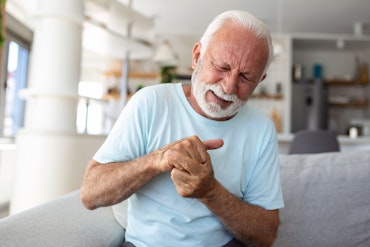 A man holds his knuckles and looks in pain