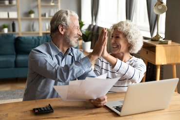 Two older people look happy as they hold paper