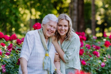 A young woman hugs an older woman in a garden