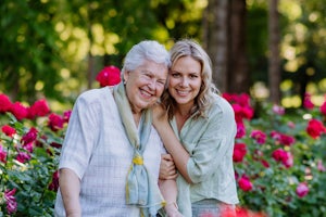 A young woman hugs an older woman in a garden