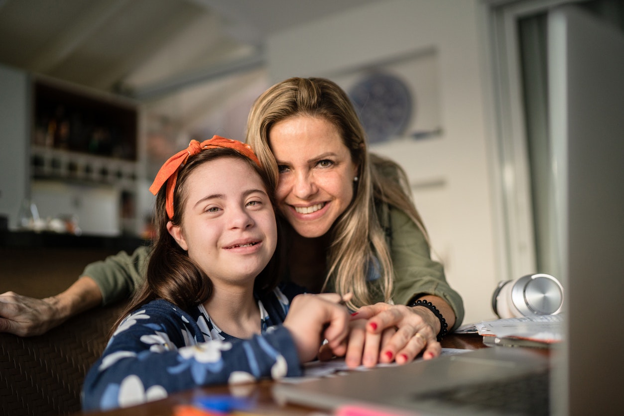 <p>Portrait of mother and special needs daughter studying at home</p>
