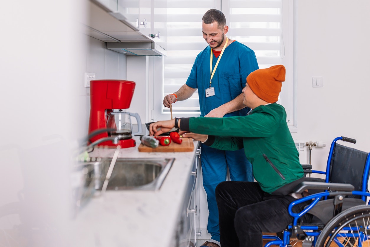 <p>Cheerful positive young Caucasian home caregiver in uniform preparing food for a patient. [Source RealPeopleGroup, istock]</p>
