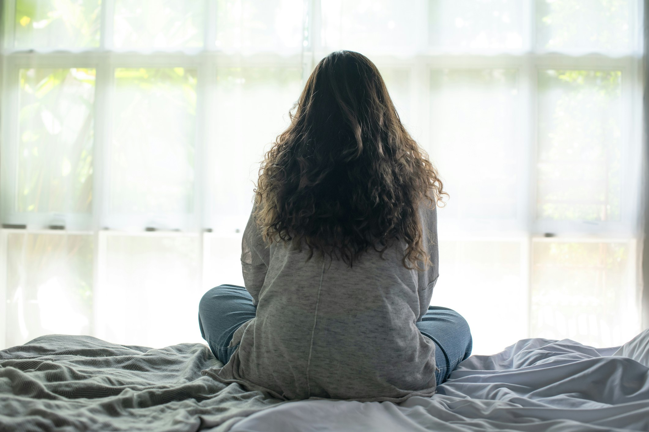 <p>Young Asian woman sitting in a bedroom, feeling sad tired and worried suffering depression in mental health. in concept of depression anxiety and insomnia. [Source amenic181, iStock]</p>
