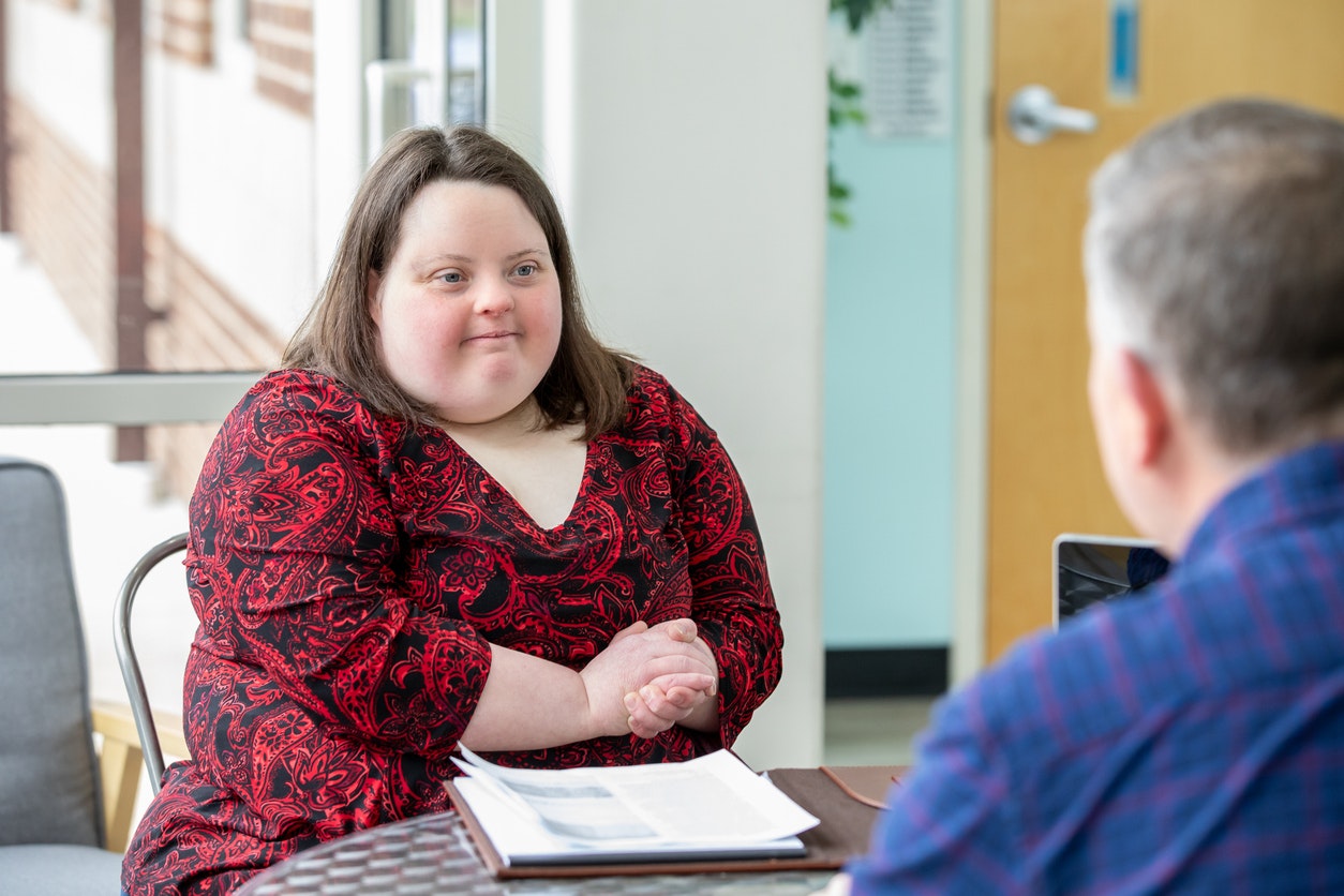 <p>A young woman with Down syndrome talking with a case manager</p>

