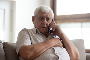 An older man phones someone and looks worried