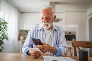 A man looks at his phone while sitting at a table