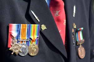 A man wearing a suit also wears multiple coloured medals