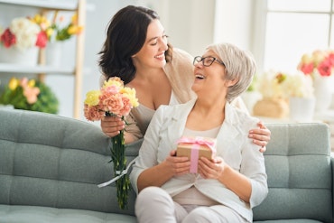 An older woman is surprised by her daughter with flowers