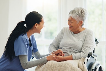 A nurse hold the hand of an older woman