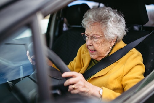 Older woman sits in car looking confused