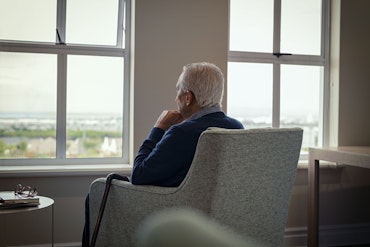 A man sits in a chair and faces the window