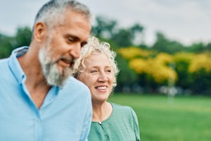 Two older people walk through a park