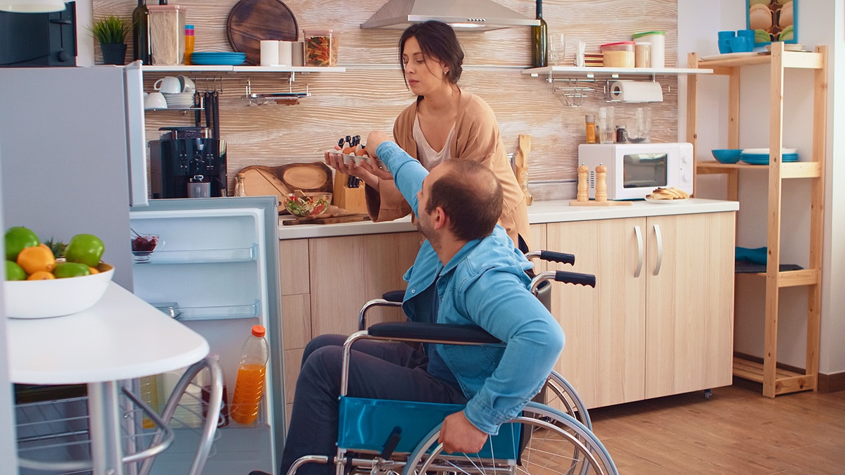 Lady helping a man in a wheelchair [Source: Shutterstock]