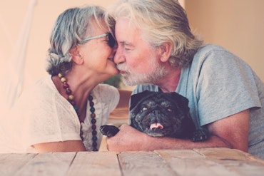 An older couple are kissing.