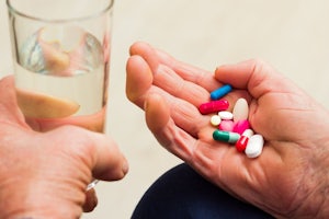 An older person's hand has tablets in it