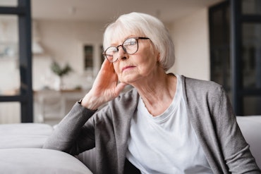 A woman with glasses looks away from the camera