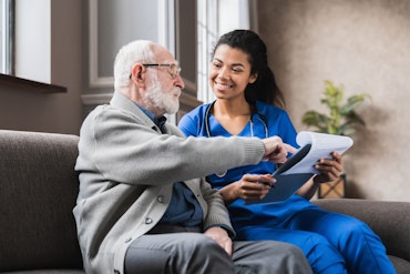 A nurse and older man look at a clipboard