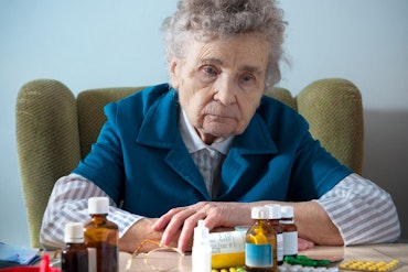 A woman in blue looks sad in front of medications