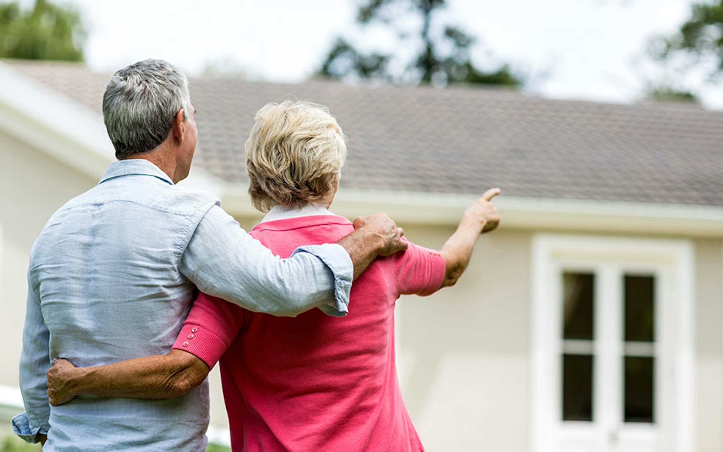 Elderly couple pointing at a house