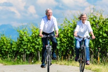 Retired couple bicycling on road near fields