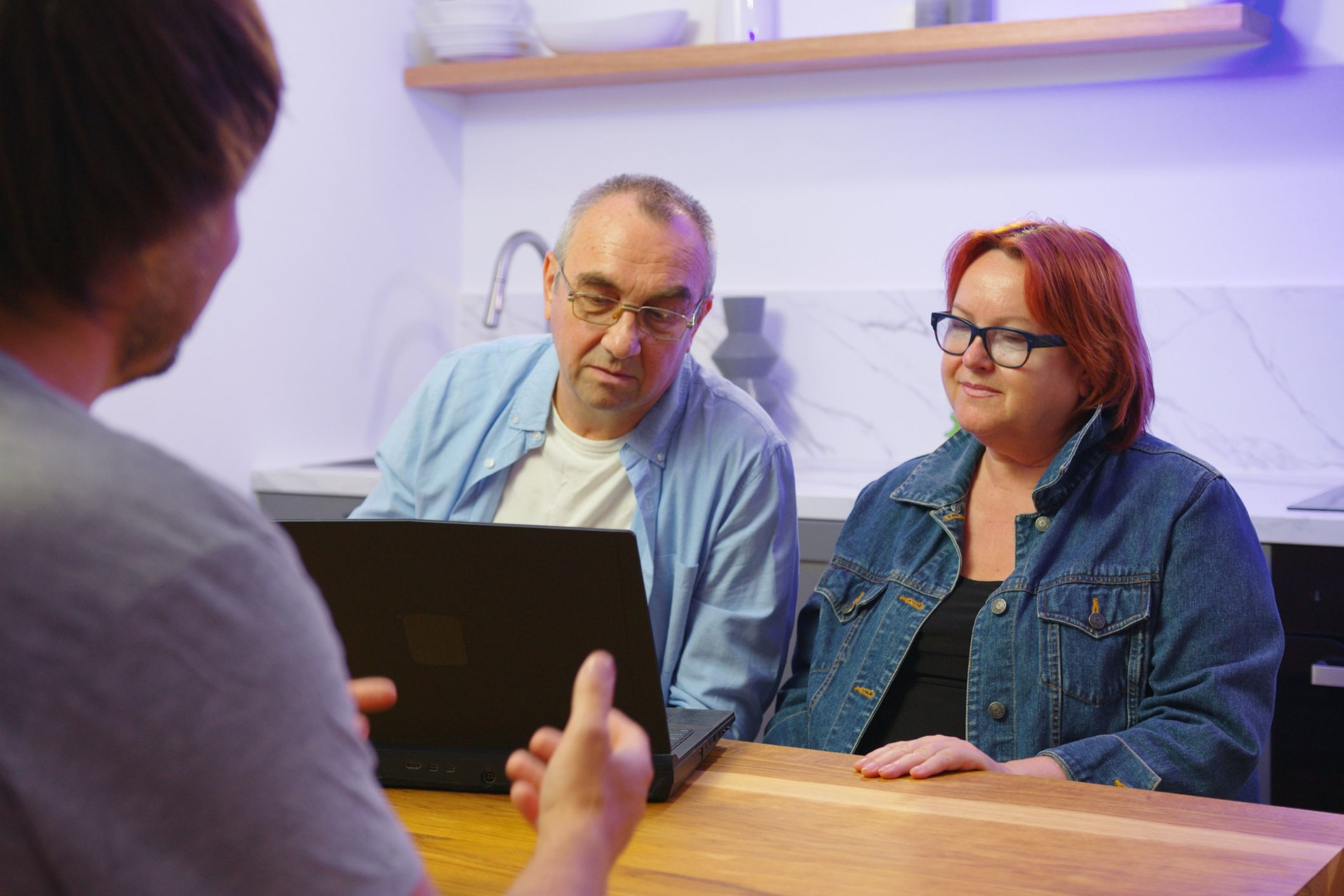 Retired couple sit across the desk from person trying to sell them something.