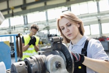 Woman working a blue-collar job with man in background